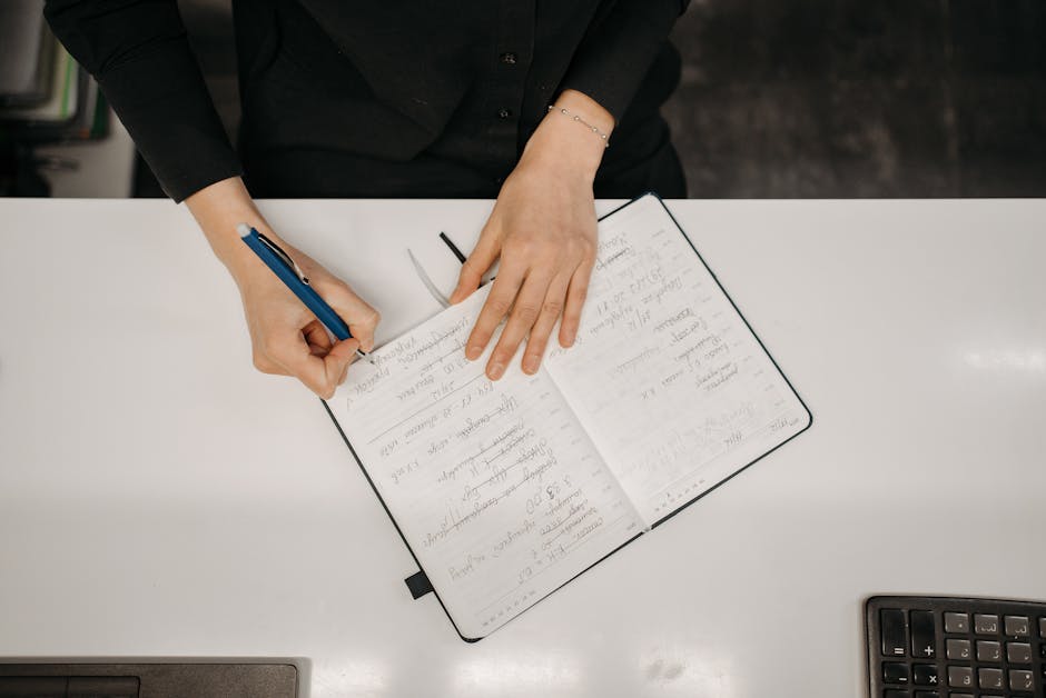 Osoba zapisująca pomysły w notatniku przy biurku.